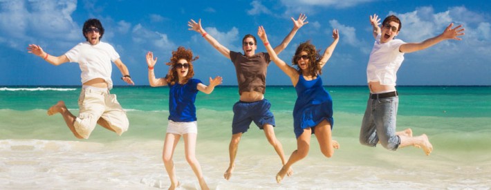 Backpackers jumping on the beach group travel