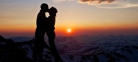 Couple kissing over a mountain sunset